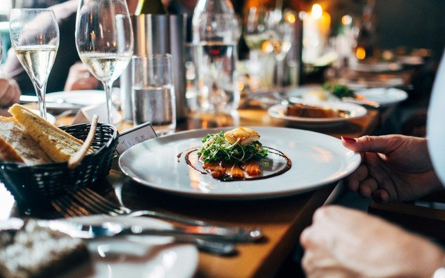 Elegantly plated dish at a fine dining restaurant table with wine glasses, representing private concierge curation