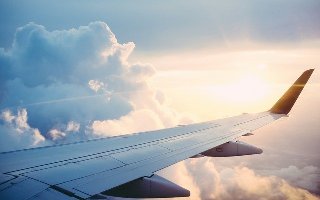 Airplane wing above clouds at sunset, representing a smoothly coordinated private arrival