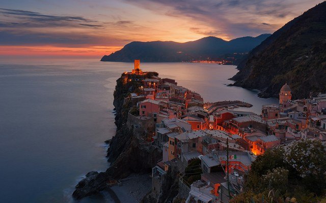 Cliff-side Italian coastal village lit at dusk overlooking the Mediterranean