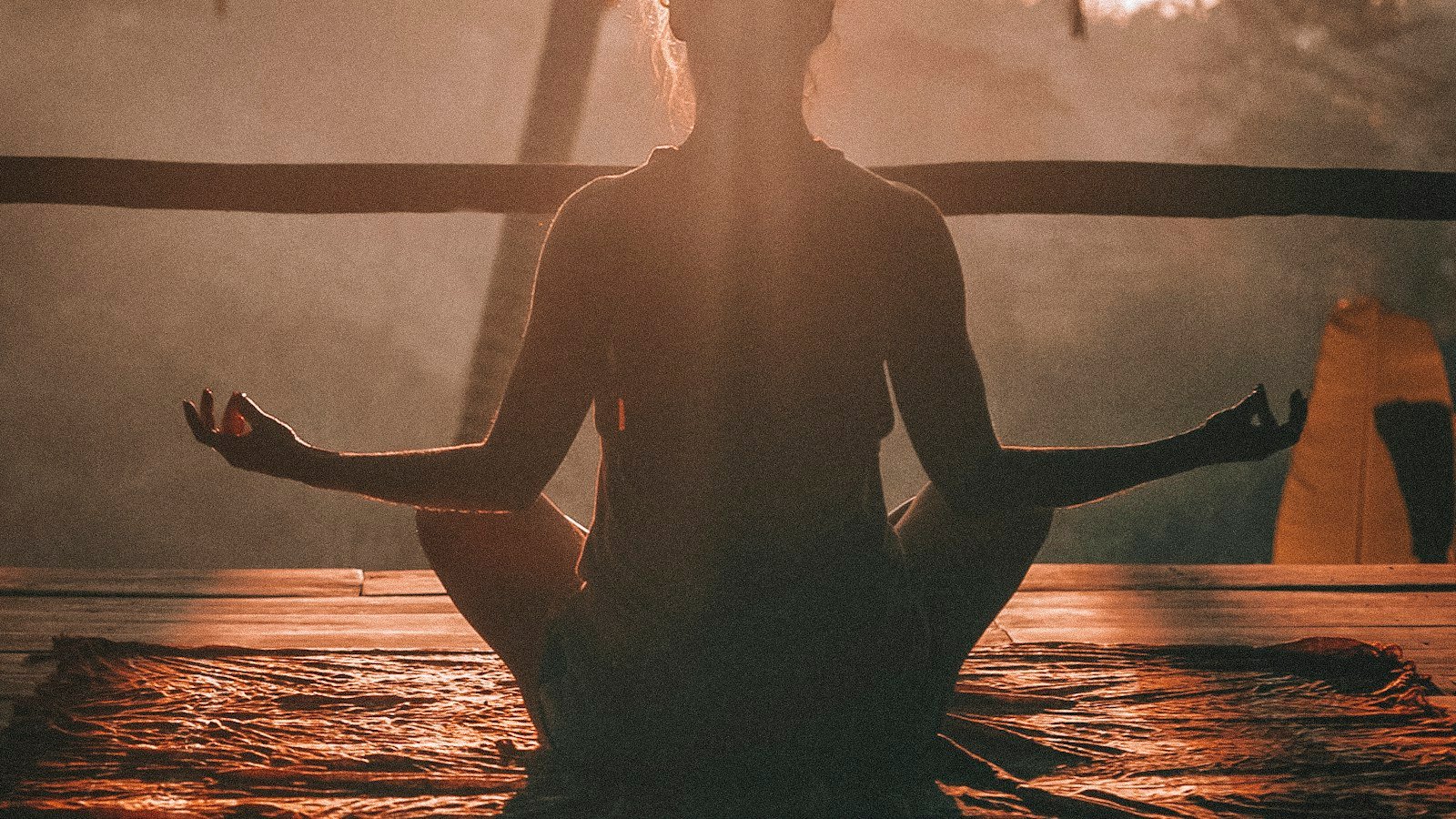 Person meditating in peaceful silhouette at sunrise, representing the calm and normalcy that discreet close protection is designed to preserve