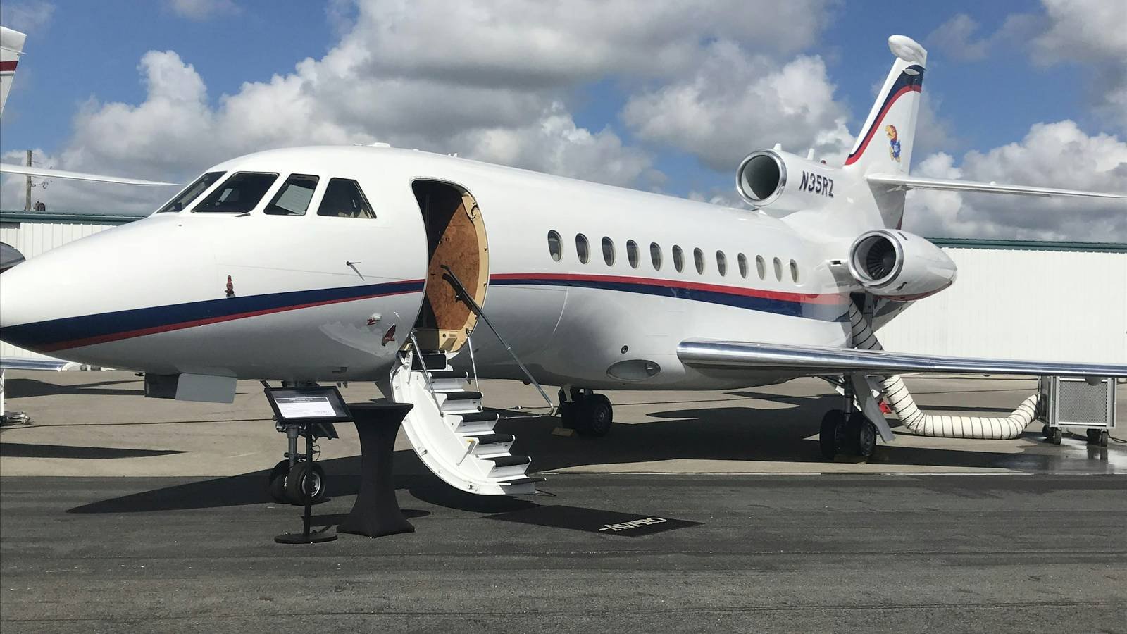 A private jet parked on the apron with its airstairs down under a bright sky