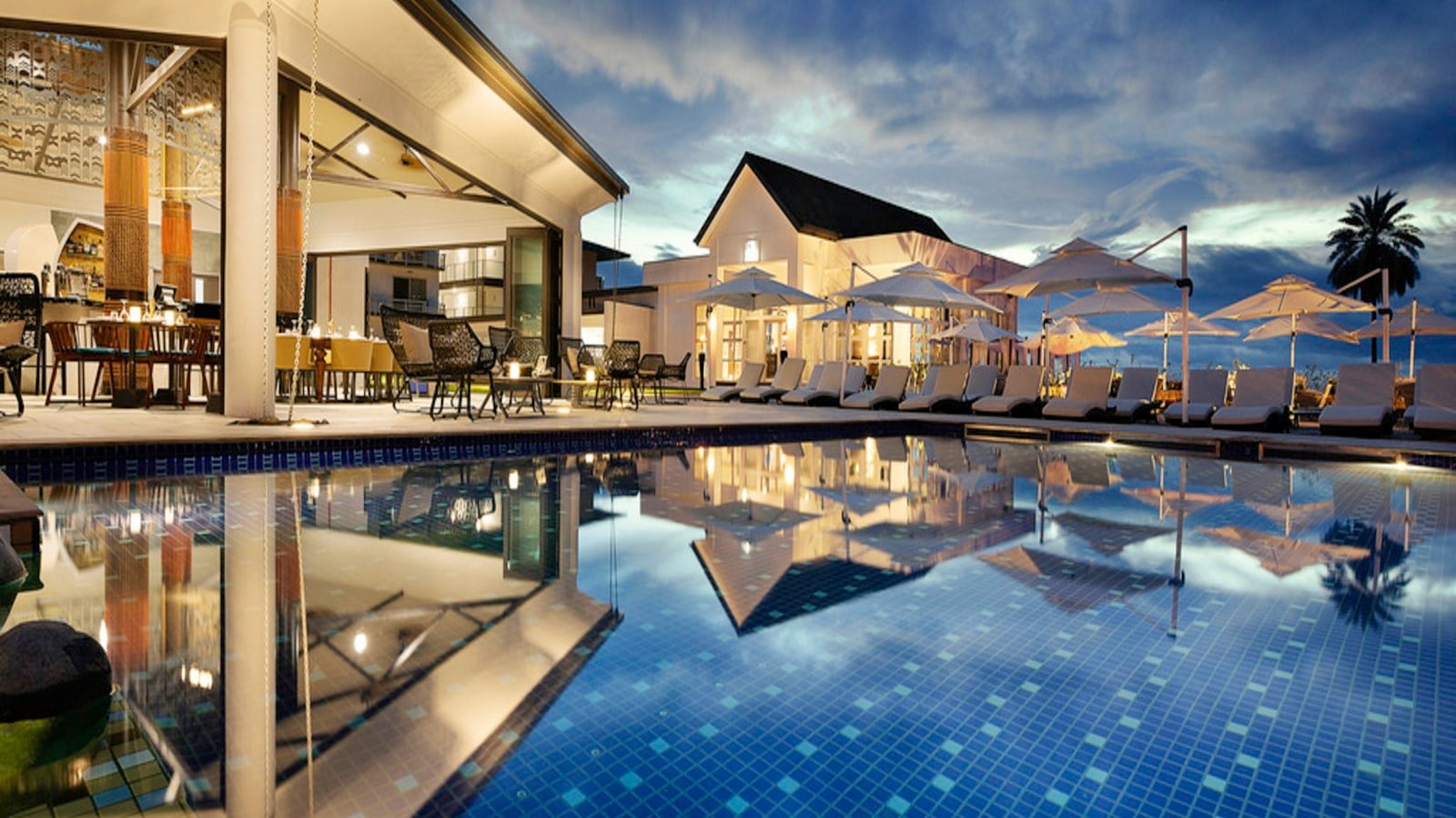 Luxury resort pool at twilight reflecting warm lights, the kind of private base that anchors a well-orchestrated multi-generational family holiday