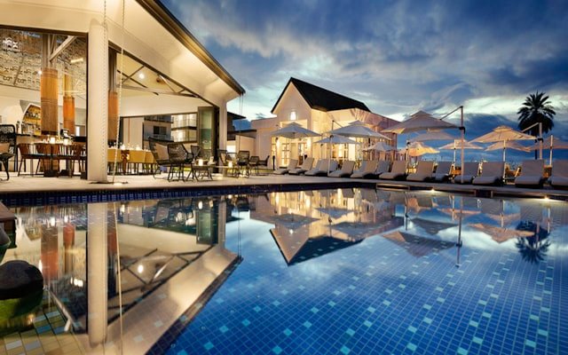 Luxury resort pool at twilight with warm reflections, the kind of private base that anchors a well-orchestrated multi-generational family holiday